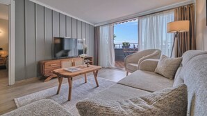 Een moderne woonkamer met een bank, televisie, houten salontafel en uitzicht op het groen.