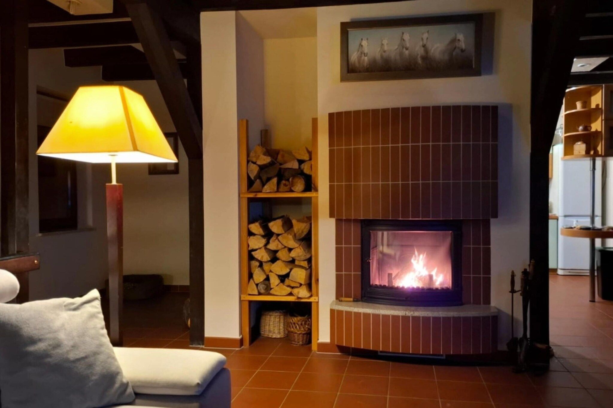 Ein gemütliches Wohnzimmer mit Kamin, Lampe und Kaminfeuerkorb mit einem Gemälde.