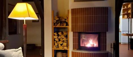 Ein gemütliches Wohnzimmer mit Kamin, Lampe und Kaminfeuerkorb mit einem Gemälde.
