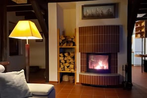A cozy living room with a fireplace, a lamp, and a fireplace mantel with a painting.