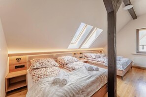 A bedroom with two beds, skylights, wooden headboards, and a radiator. - Large, comfortable holiday home with a garden (Zatom)