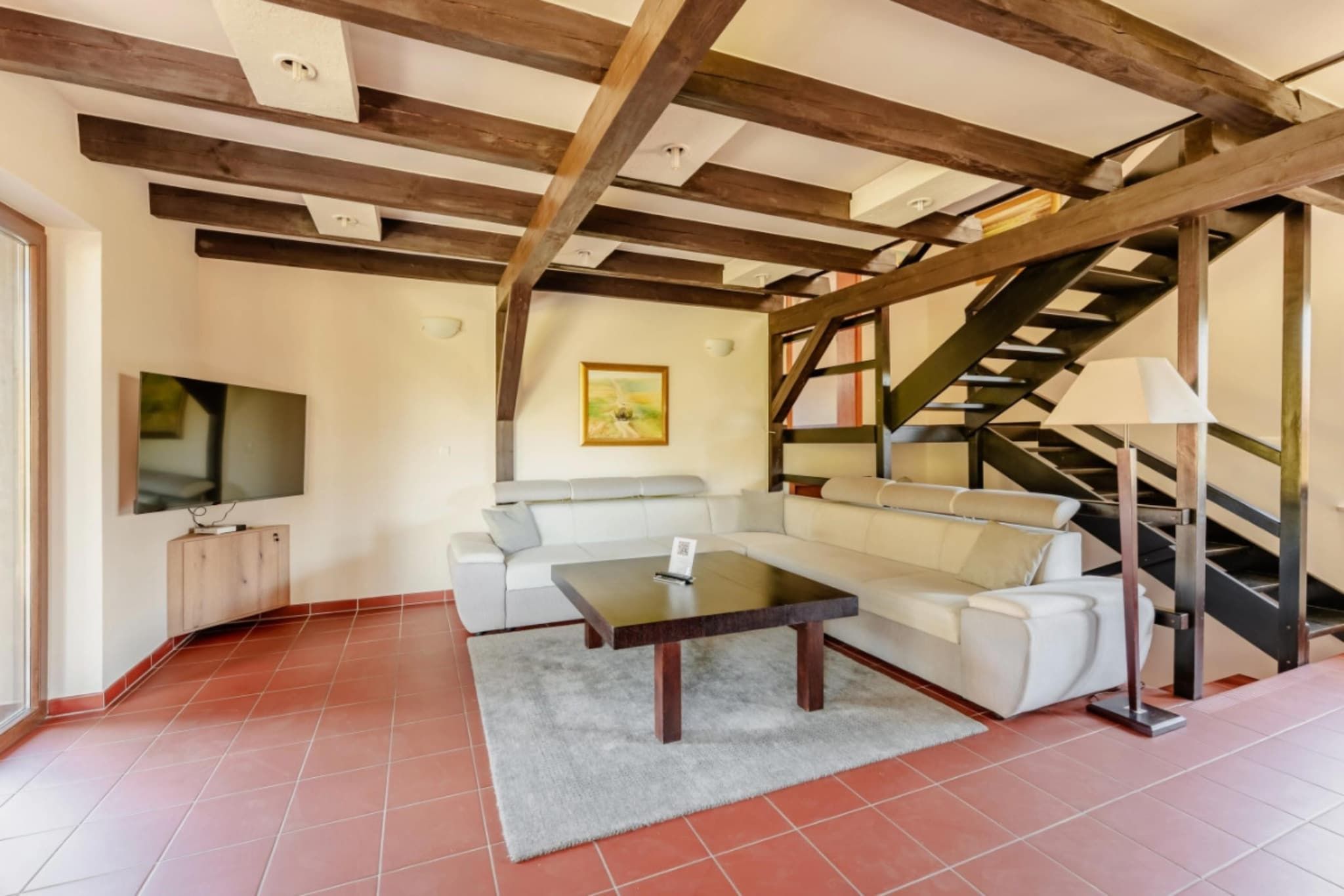 Una sala de estar con sofá, mesa de centro y una escalera.