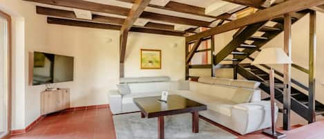Una sala de estar con sofá, mesa de centro y una escalera.
