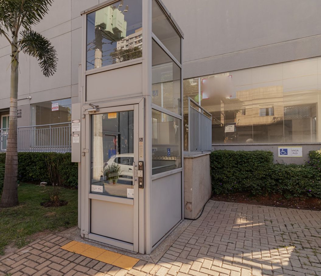 A modern building with a glass entrance, a wheelchair accessibility sign, and a paved sidewalk.