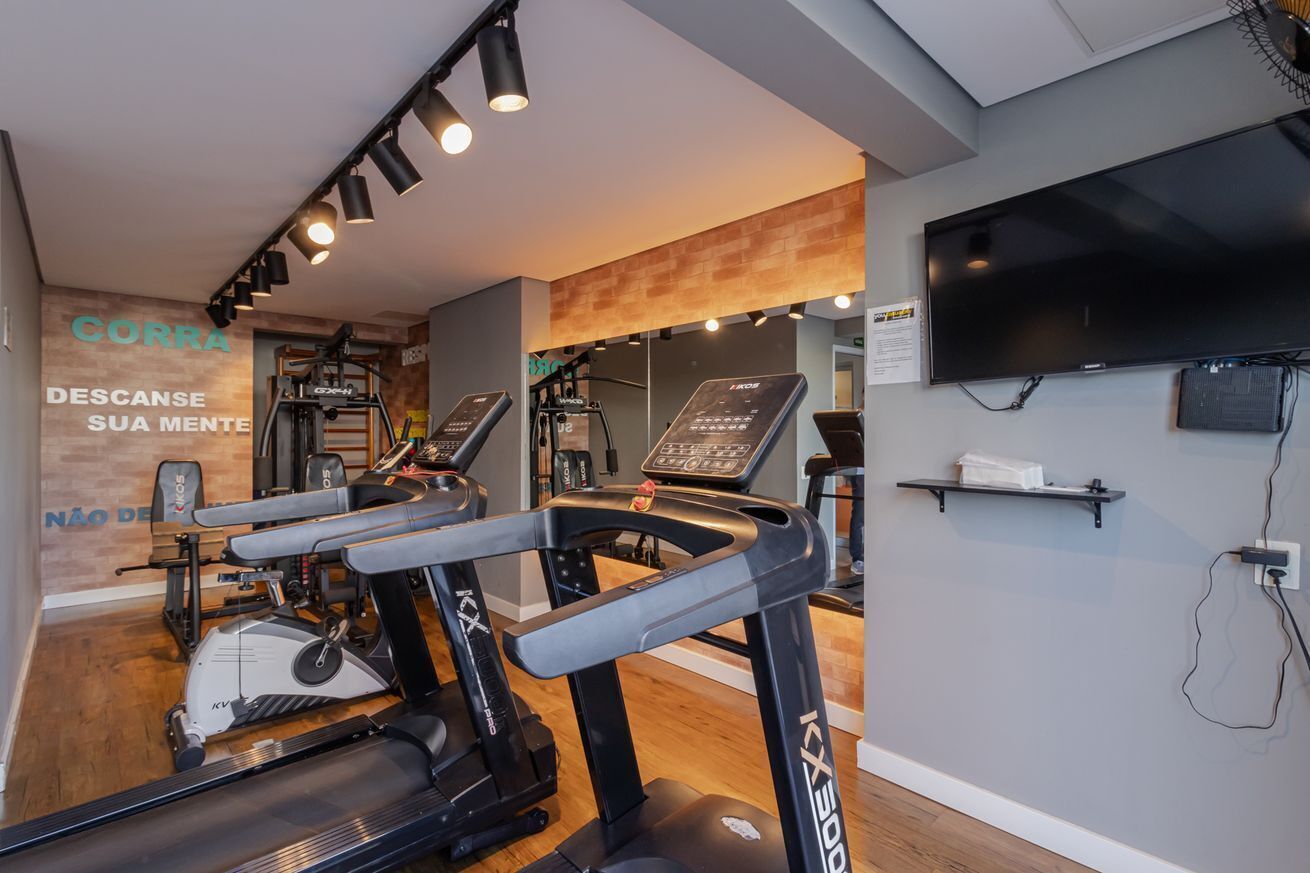 A gym with treadmills, a stationary bike, and a wall-mounted TV.