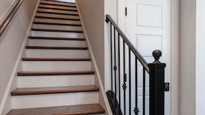 Una escalera de madera con barandillas negras que lleva a una puerta blanca.