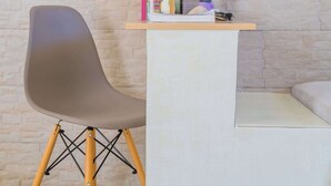 Habitació moderna amb una cadira gris, un taulell blanc i una paret de maó.