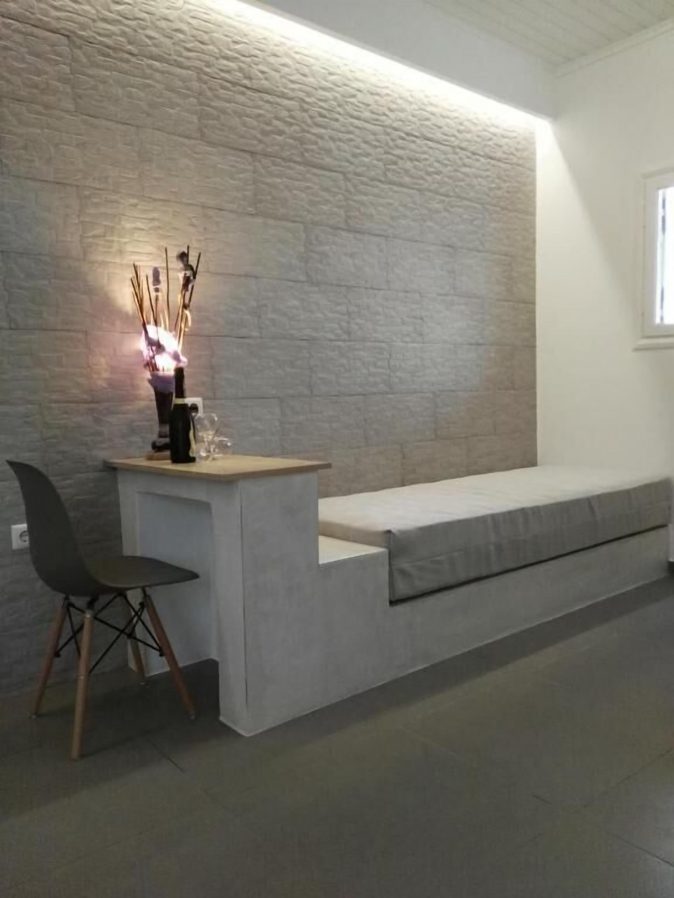 A reception area with a stone wall, a reception desk, a bench, and a chair.