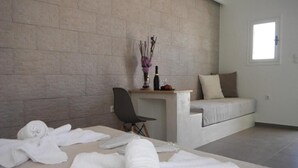 Habitació moderna amb paret de maó, un llit, una taula de treball amb cadira i una finestra.
