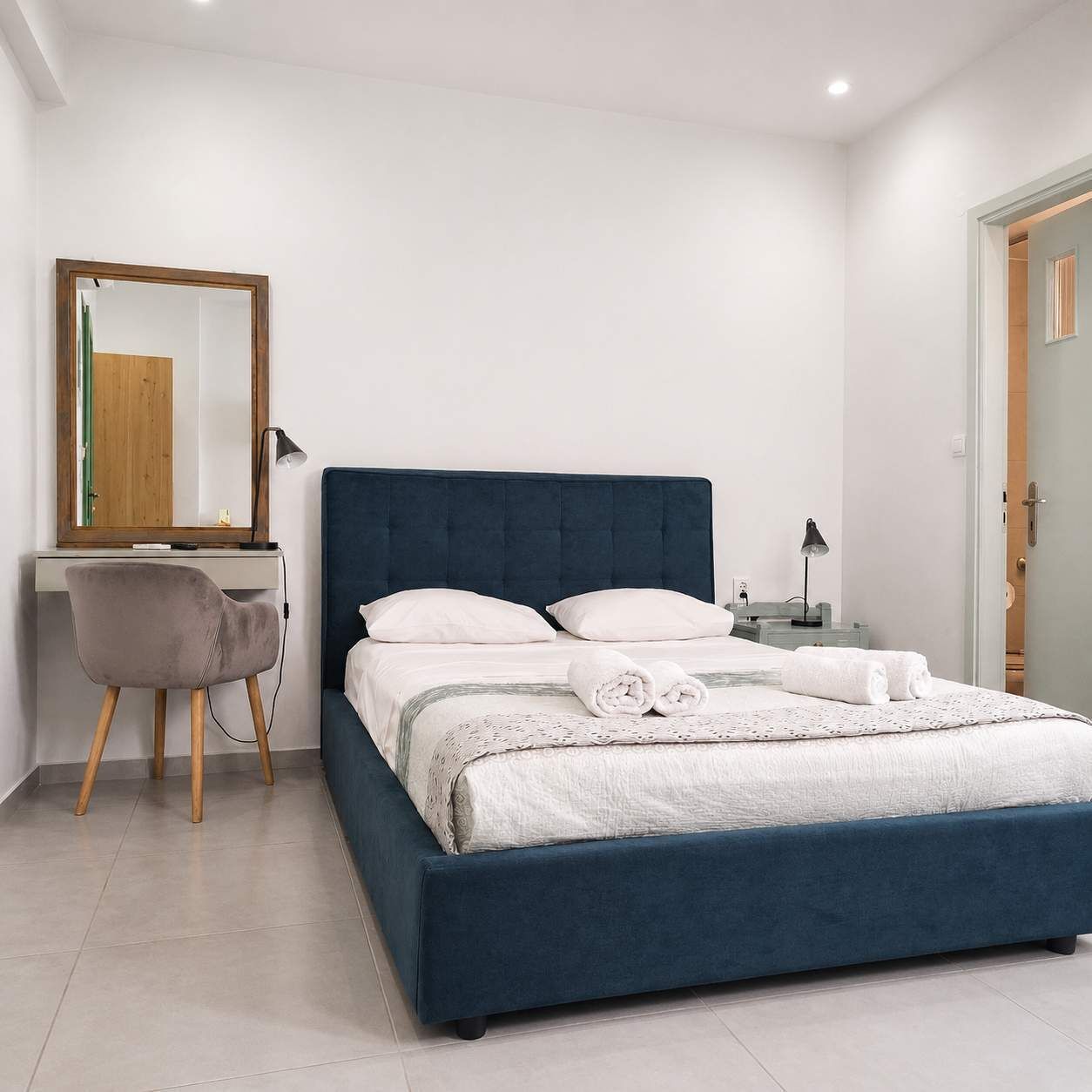 Un dormitorio con cama, escritorio, silla y espejo.
