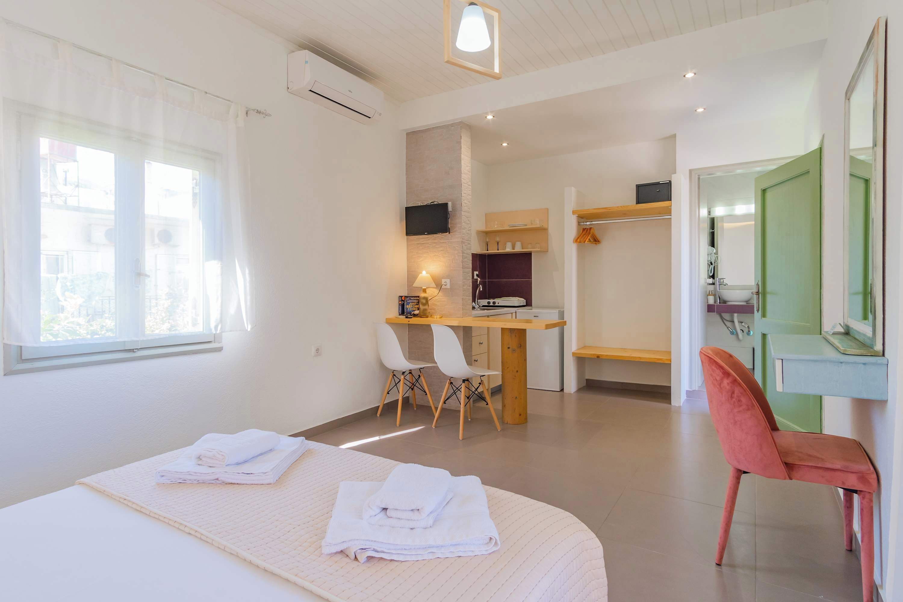 Une chambre d’hôtel avec un lit, un bureau, une chaise, un miroir et une salle de bain.