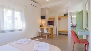 Une chambre d’hôtel avec un lit, un bureau, une chaise, un miroir et une salle de bain.