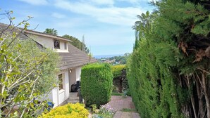 Una propiedad residencial con un camino pavimentado, un jardín cuidado y vistas del paisaje circundante.
