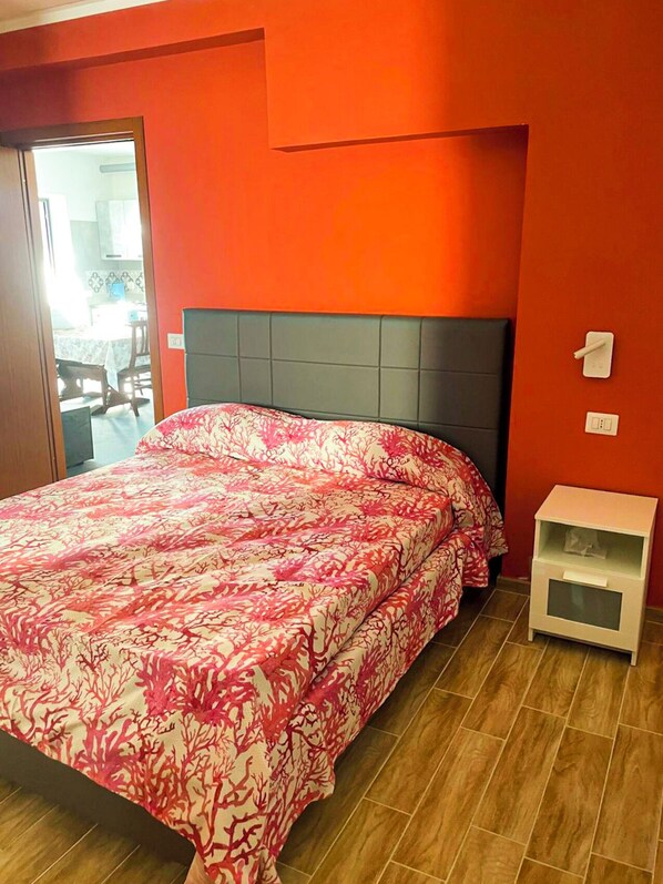 Ein Schlafzimmer mit einem Bett, einem Nachttisch und einer Tür zu einem anderen Raum.