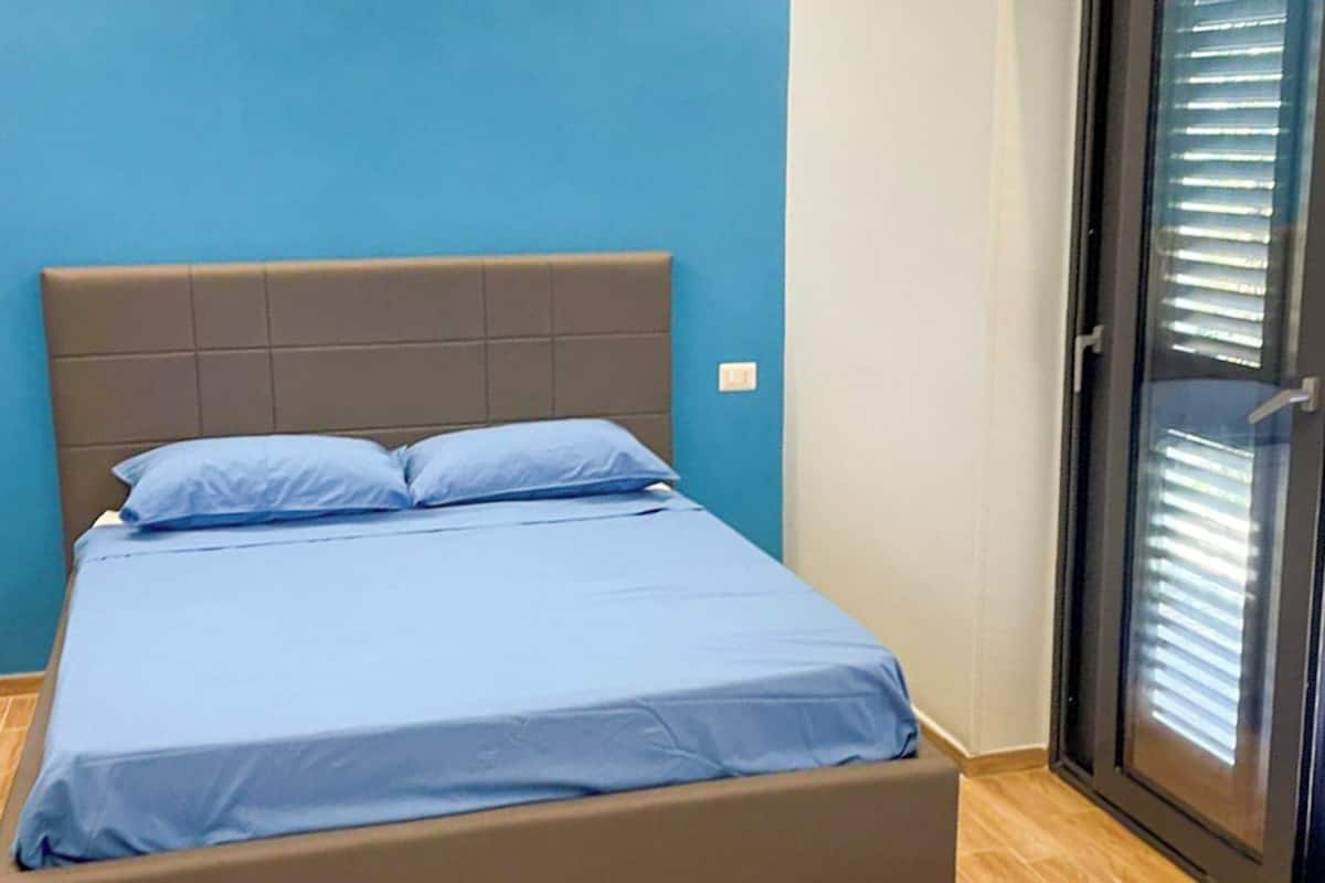 A bed with a headboard, a blue mattress, and two pillows.