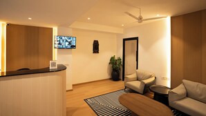 Un área de recepción moderna con un mostrador de recepción, zona de estar y una pantalla de televisión.