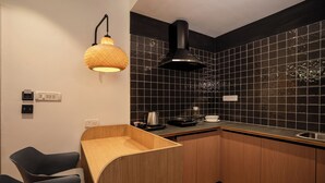 Una cocina moderna con salpicadero de azulejos negros, armarios de madera, extractor de aire negro y una lámpara colgante de fibras.