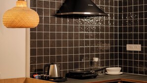 Una cocina moderna con una campana extractora negra, una lámpara colgante tejida y un salpicadero de azulejos.