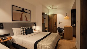 Una habitación de hotel moderna con una cama grande, mesitas de noche, un escritorio, una silla, un armario y un ventilador de techo.