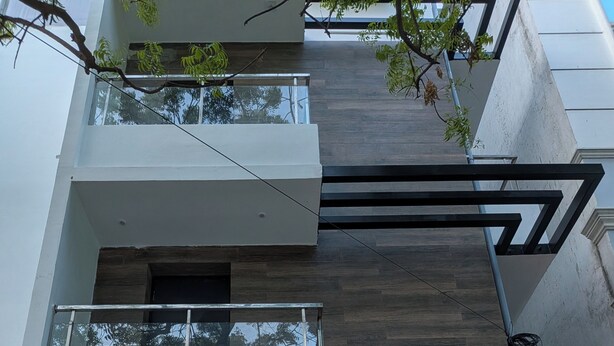 Un edificio de varios pisos con diseño moderno, que cuenta con balcones, una recepción y un letrero que indica un restaurante.