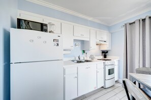 Een keuken met witte kastjes, een magnetron, een spoelbak en een oven.