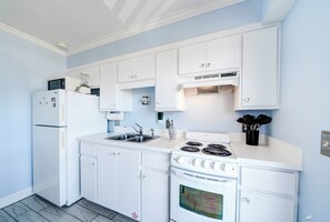 Une cuisine avec des meubles blancs, une cuisinière, un four à micro-ondes et un réfrigérateur.