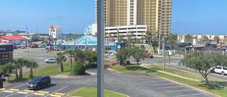 A view from a balcony overlooking a parking lot with a large hotel in the background.