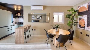 A modern kitchen with a dining area, a large mirror, and a potted plant.