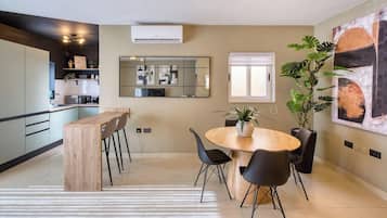 Una cocina moderna con comedor, un espejo grande y una planta en maceta.