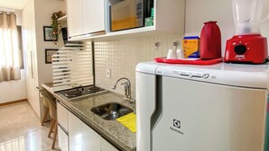 Une cuisine équipée d’un four à micro-ondes encastré, d’un mixeur rouge et d’un évier.