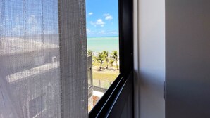 Una ventana con vista a una playa y palmeras.