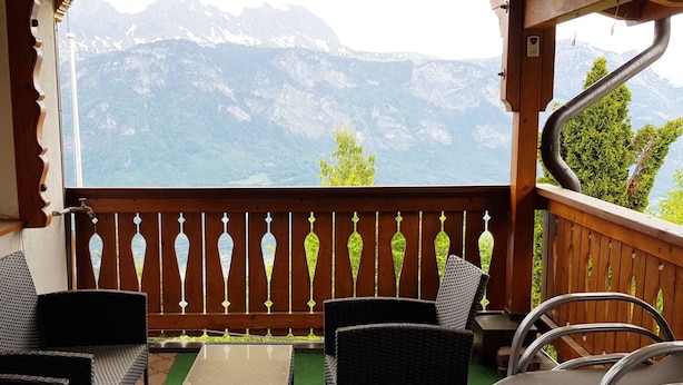 A balcony with wicker furniture, a table, and a view of mountains. - Haus Gonzenblick, (Flumserberg Tannenheim), by Interhome (Flumserberg Tannenheim)