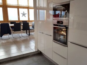 A kitchen with white cabinets, a built-in oven, and a dining area with chairs and a table.