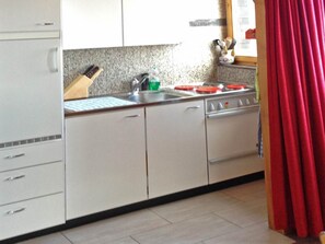 Une cuisine avec des meubles blancs, un évier, une cuisinière et un bloc à couteaux.