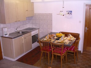 A compact kitchen with a sink, stove, and cabinets. There is a dining table with chairs and a small chandelier. - Ferienhaus Tschudiboden, (Flumserberg Tannenheim), by Interhome (Flumserberg Tannenheim)