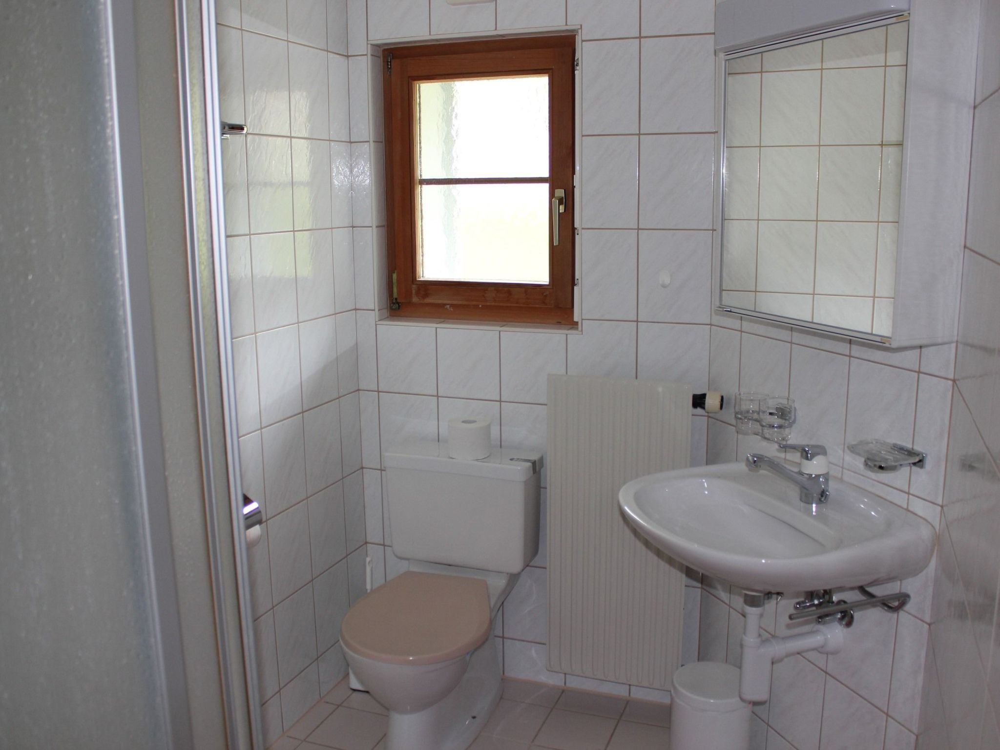 A small bathroom with a toilet, sink, and a window.
