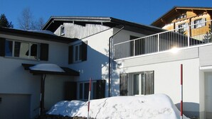 Un bâtiment à deux étages, doté de fondations en pierre, d’un balcon et d’un sol recouvert de neige.