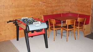 Una mesa de fútbol de mesa y una mesa roja con cuatro sillas de madera en una habitación con paredes de madera.