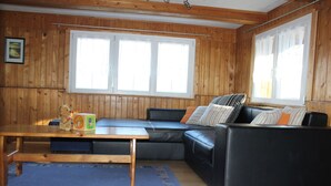 Une pièce aux murs en bois, avec un canapé en cuir noir, une table en bois et un tapis bleu.