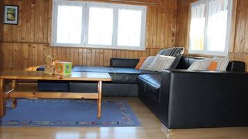 Une pièce aux murs en bois, avec un canapé en cuir noir, une table en bois et un tapis bleu.