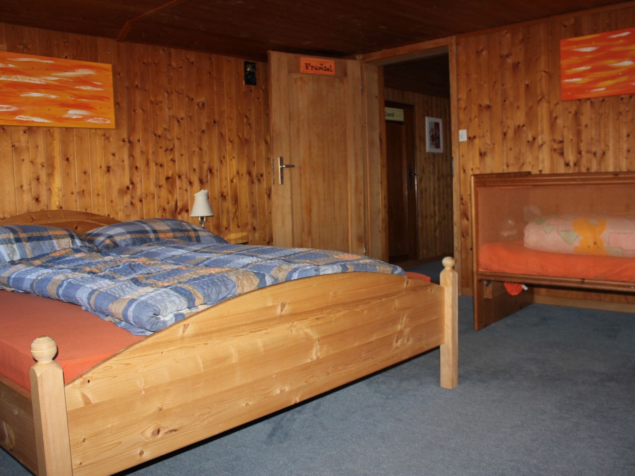 Une pièce en bois avec un lit, une table de chevet et une porte portant l’inscription « Früspol ».
