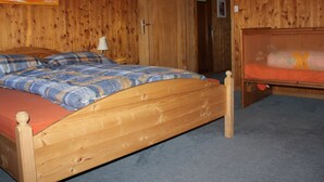 Une pièce en bois avec un lit, une table de chevet et une porte portant l’inscription « Früspol ».
