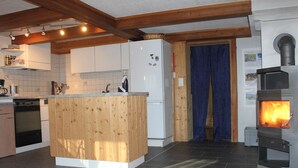 Une cuisine avec des meubles de rangement en bois, un réfrigérateur blanc, une cuisinière et un rideau bleu.