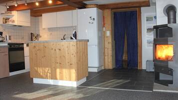Une cuisine avec des meubles de rangement en bois, un réfrigérateur blanc, une cuisinière et un rideau bleu.