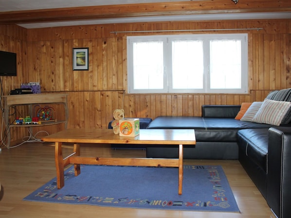 A wooden-paneled room with a sofa, a small table, and a window.