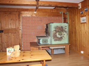 A rustic room with wooden walls, a brick fireplace, a vintage green refrigerator, and a wooden table with a teddy bear. - Ferienhaus Fäsch, (Flumserberg Bergheim), by Interhome (Flumserberg Bergheim)