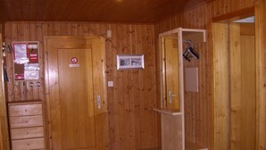 Ein Zimmer aus Holz mit Holztür, einem Kleiderständer und einer kleinen Ablagefläche.
