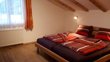A bedroom with a wooden bed, a window with curtains, and a radiator.