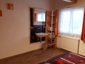 A small bathroom with a sink, mirror, and towel rack. There is a window with curtains and a radiator. - Ferienhaus Tschudiboden, (Flumserberg Tannenheim), by Interhome (Flumserberg Tannenheim)