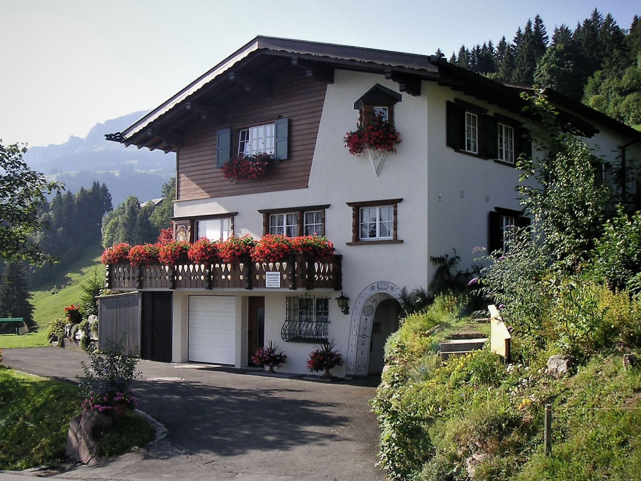 Un immeuble de deux étages doté d’un balcon, d’un garage et offrant une vue sur la montagne.